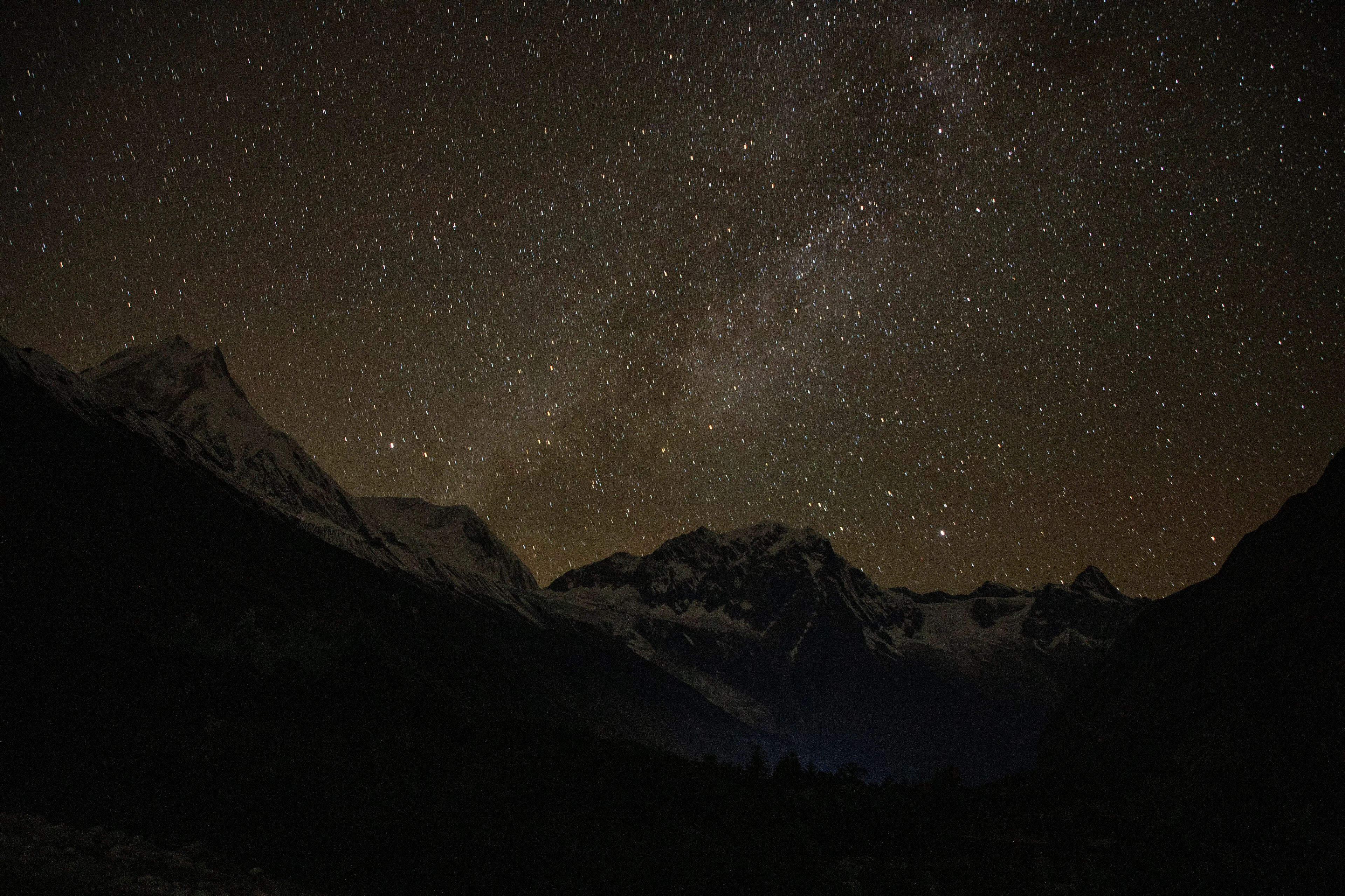 Trekkers around a campfire beneath a star-filled Himalayan sky