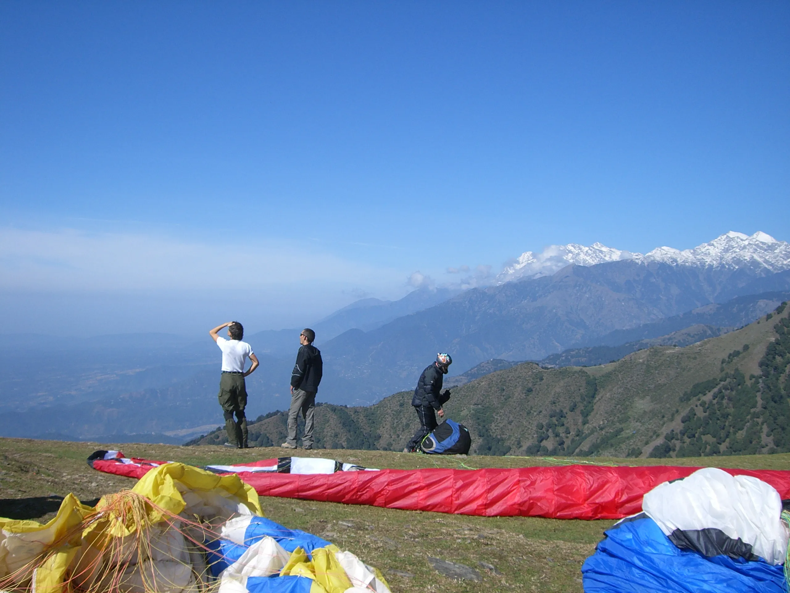 Paragliders and trekkers against a Himalayan backdrop