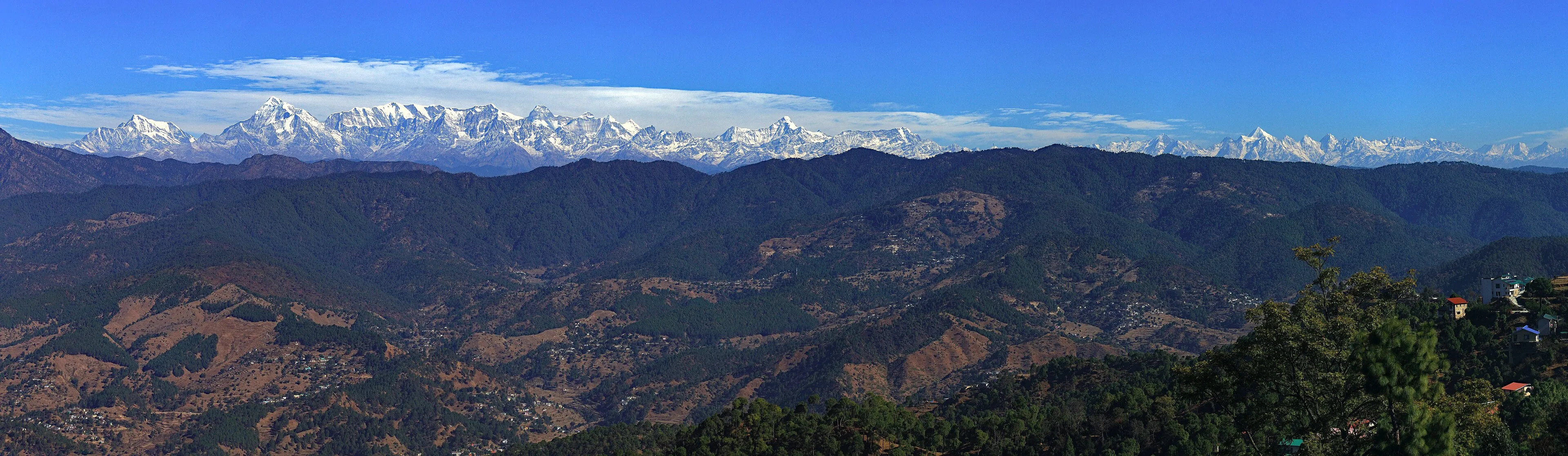A mountain hut with a signpost against Himalayan peaks